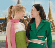 two women standing next to each other in front of a building