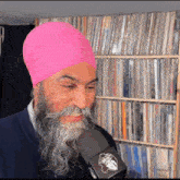 a man with a beard and a pink turban is holding a microphone
