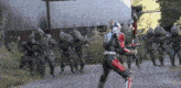 a group of soldiers are walking down a road and one of them is holding a large sword