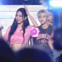 a woman in a pink shirt with the word love on it stands next to a man in a black shirt with the word town on it .