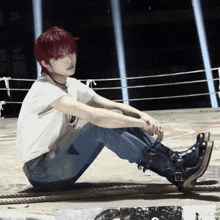 a young man with red hair is sitting on the ground in a boxing ring
