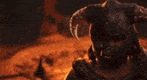 a man wearing a helmet with horns on it stands in front of a fire