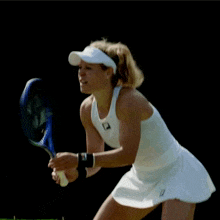 a woman is holding a tennis racquet and wearing a white top with the word fila on it