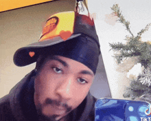 a man wearing a hat and a headband is looking at his phone with tiktok written on it