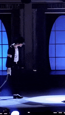 a man in a black and white suit is walking on a stage