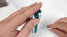 a person is holding a string of blue and white beads between their fingers