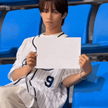 a baseball player with the number 9 on his jersey holds a piece of paper