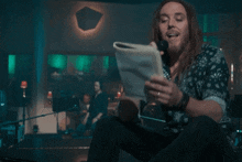 a man with long hair is holding a microphone in front of a sign that reads lemons into lemonade