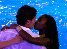 a man and a woman are kissing in front of a blue background