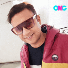 a man wearing sunglasses and a red jacket is smiling