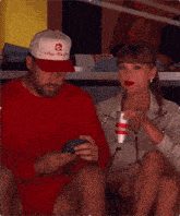 a man and a woman are sitting next to each other and the man is wearing a hat that says washington redskins