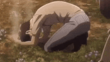 a man is kneeling down in the grass in a field .
