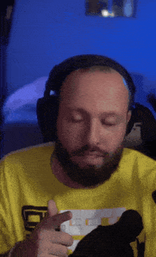 a bald man with a beard wearing headphones and a yellow shirt with the letter e on it