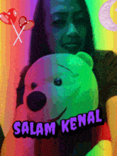 a woman is holding a teddy bear with the words salam kenal on the bottom