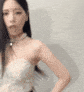 a woman in a white strapless dress is standing in front of a white wall .