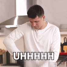 a man in a white shirt is standing in a kitchen with the word uhhhh on the bottom right