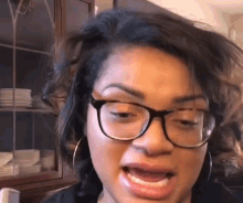 a close up of a woman wearing glasses and hoop earrings