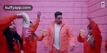 a man in a pink jacket is dancing with a group of people in red jackets .