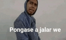 a man in a blue hoodie is standing in front of a white wall with the words pongase a jalar we .