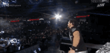 a man in a black shirt is standing in front of a crowd at a wrestling show