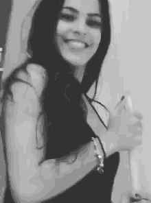a woman in a black dress is smiling and giving a thumbs up .