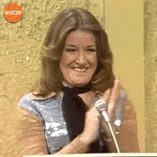 a woman is smiling and clapping in front of a microphone with buzzr written in the corner