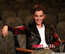 a woman in a leather jacket is sitting in a row of seats with teen vogue written on the seats