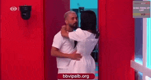 a man and a woman are hugging each other in a red doorway .