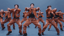 a group of men in brown pants with stars on them are dancing in a line