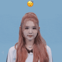 a girl with long red hair is holding her hands up in front of a blue background