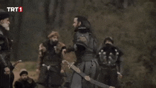 a man with a beard and a black turban is standing in front of a group of men .