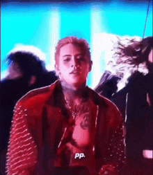 a man with a tattoo on his chest is standing in front of a crowd and says pp .