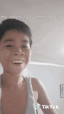 a young boy in a tank top is smiling and making a face .