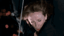 a woman is hanging upside down on a rope with her eyes closed