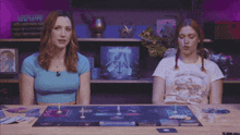 two women sitting at a table with a board game in front of them and a sign that says " good time society "