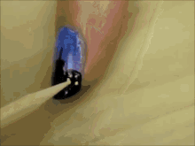 a close up of a nail being painted with blue and black