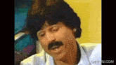 a man with a mustache is making a funny face in a video .