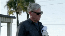 a man wearing sunglasses holds a cup of coffee