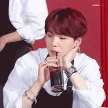 a young man with red hair is drinking a glass of soda with a straw