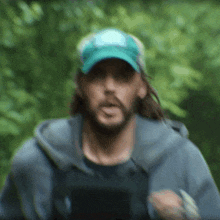 a man with long hair wearing a blue hat