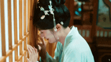 a woman with a bun on her head is leaning against a wooden wall