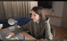 a woman wearing headphones sits at a desk with a computer mouse
