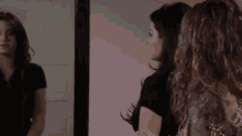 two women are looking at themselves in a mirror .