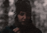 a woman wearing a scarf and a hat looks down