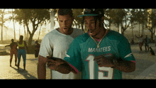 a man in a manatees jersey looks at a cell phone