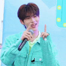 a young man in a green jacket is holding a microphone in his hand and smiling .