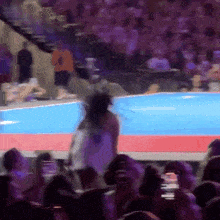 a woman in a white dress is walking on a stage in front of a crowd of people .