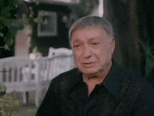 a man in a black shirt is sitting in front of a tree