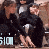 two girls are squatting on the floor with their hands on the floor .