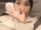 a close up of a woman 's hand covering her mouth while sitting in a chair .